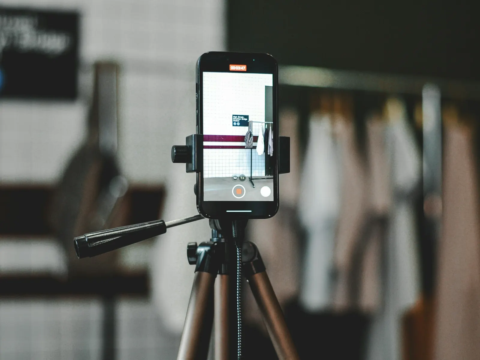 Smartphone on a tripod recording a clothing rack for a product video